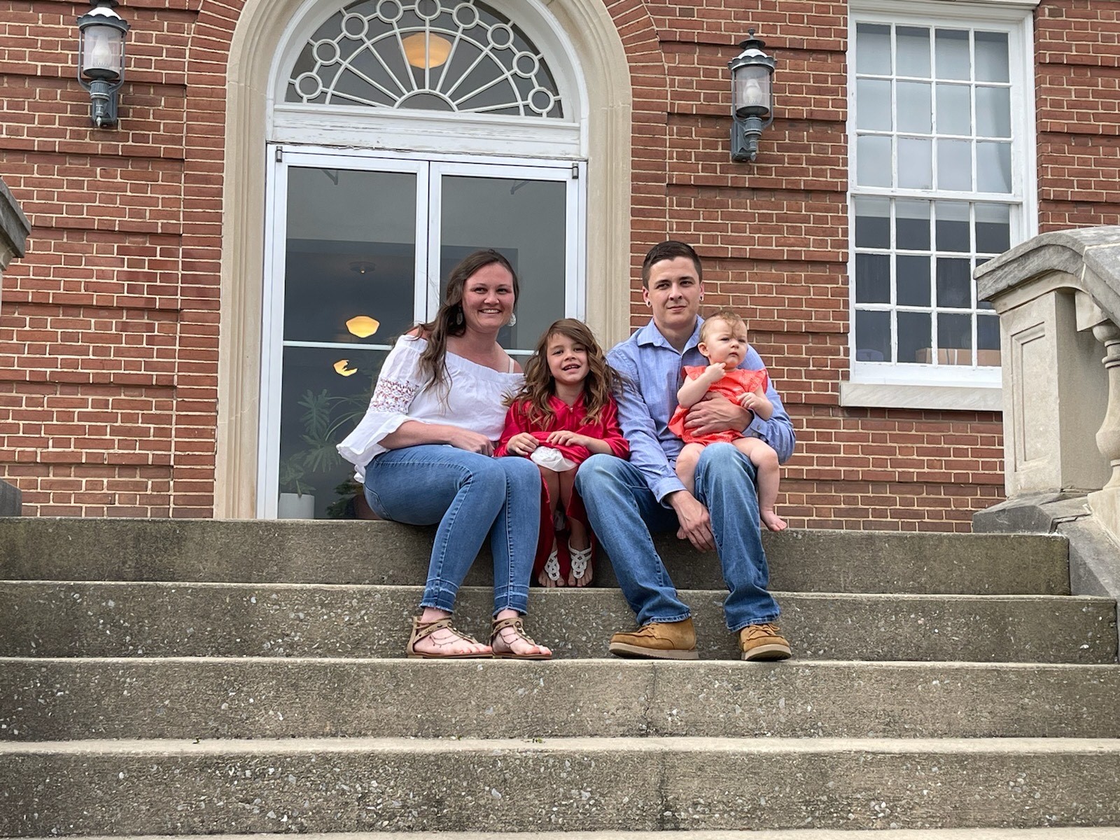 Family of four sitting on steps smiling