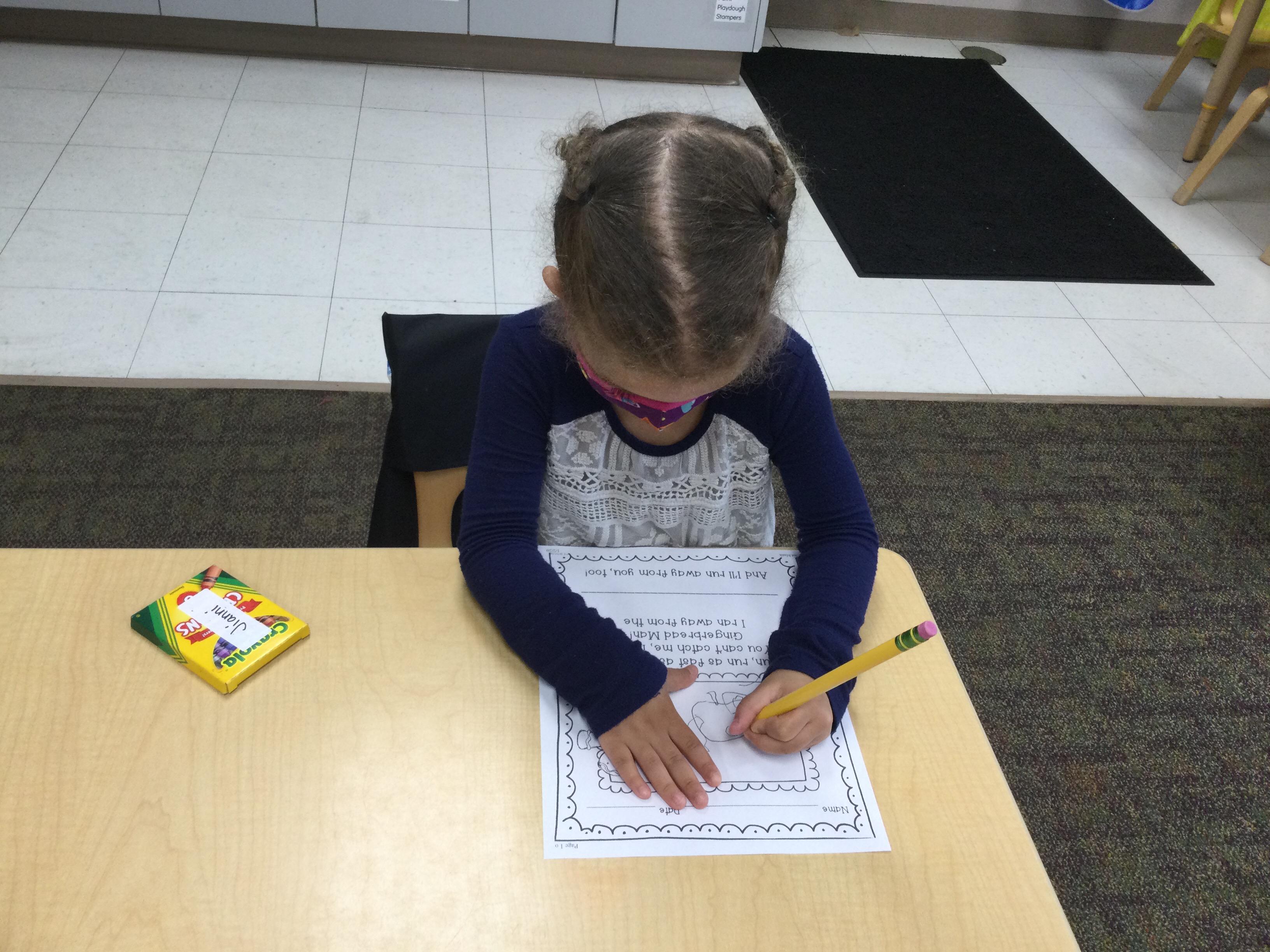 Young girl sitting at a table writing.