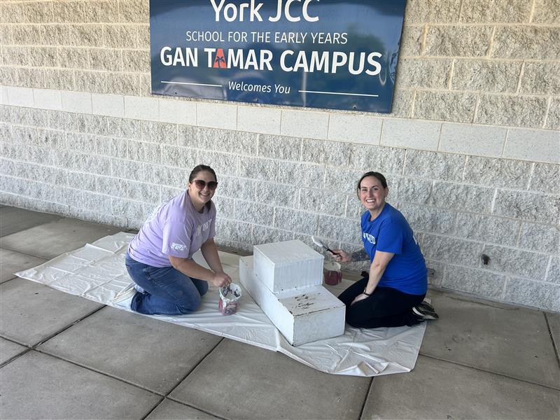 Two members smiling while painting.