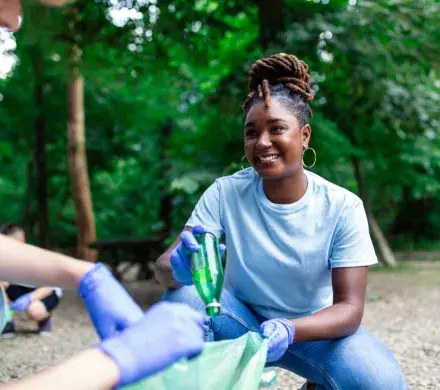 Woman picking up trash smiling.