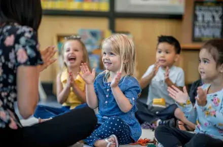 Children clapping with their teacher.