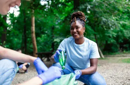 Woman picking up trash smiling.