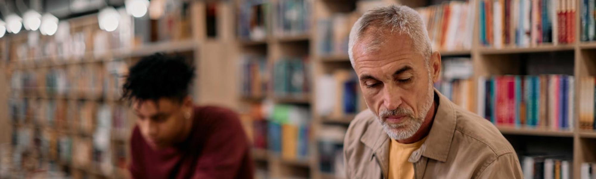 man sitting at laptop reading papers.