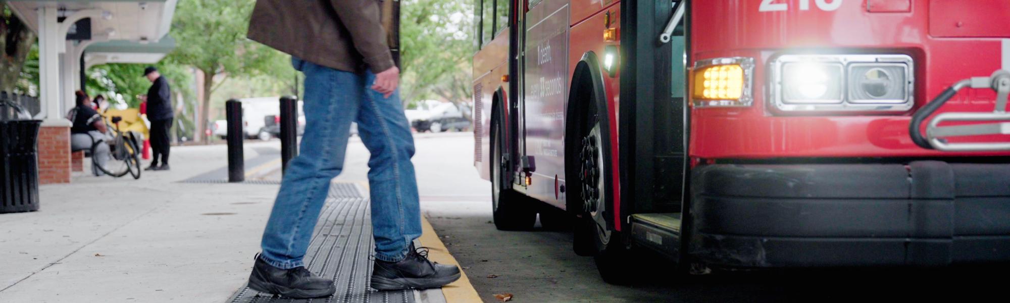 Man walking to get on a bus.