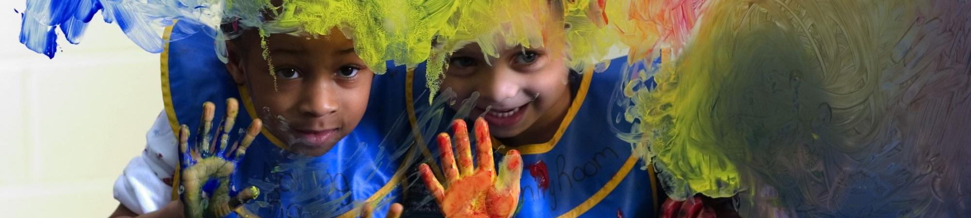 two children finger painting on glass