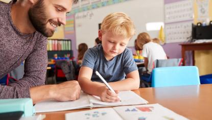 Teacher helping student at their desk.