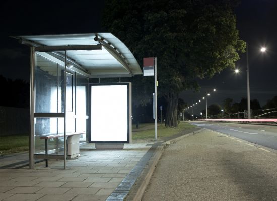 Bus stop illuminated by a streetlamp at night
