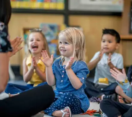 Children clapping with their teacher.